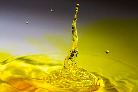 Clear water drop on a yellow tinted water.の写真素材