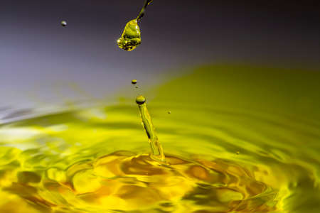 Clear water drop on a yellow tinted water.の写真素材