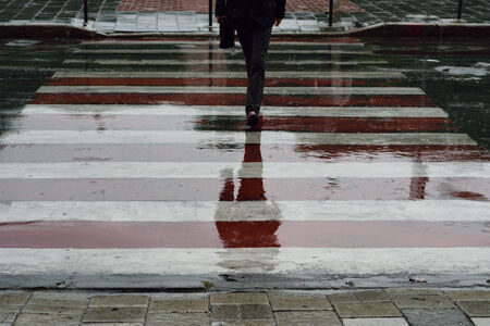 Reflections of people crossing the road in puddlesの写真素材