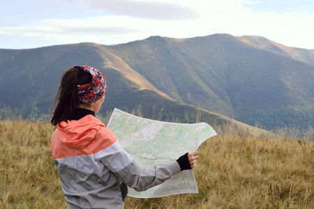 Girl tourist looking on a map in the mountainsの写真素材