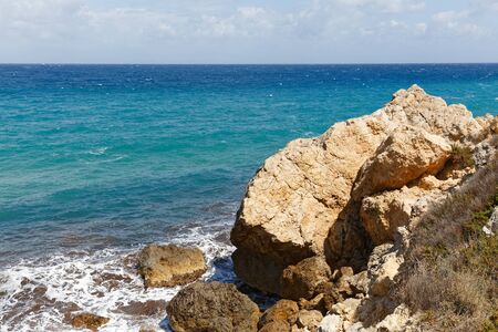 Rocky seashore of the island Gozo in Malta in the middle of mediterranean sea with vivid colors of stones and waterの写真素材