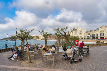 Biarritz, France, April 18, 2022. Tourists drinking on a terrace next to the Grand Plage, in the city of Biarritz.のeditorial素材