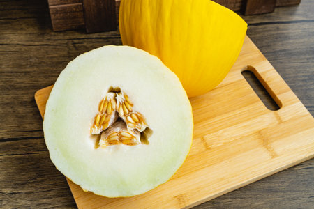 Tasty yellow melon cut in half, on wooden board.の写真素材