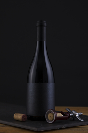 Isolated Red Wine Bottle in a Black and Wood Background, fresh and Clean with Black Capsule with Black Labelの写真素材