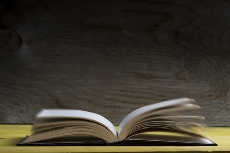 Side View of an open book lying in front of wooden backgroundの写真素材
