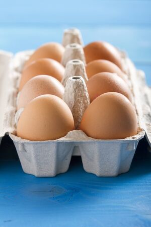 Eggs in the package on blue wooden tableの写真素材