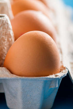 Eggs in the package on blue wooden tableの写真素材