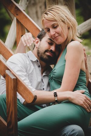 Young beautiful couple flirting sitting on stairs in a gardenの写真素材