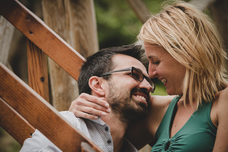 Young beautiful couple flirting sitting on stairs in a gardenの写真素材