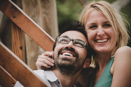 Young beautiful couple flirting sitting on stairs in a gardenの写真素材