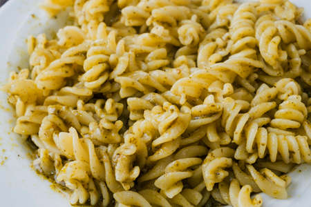Plate of fusilli pasta with pesto sauce on a wooden table の写真素材