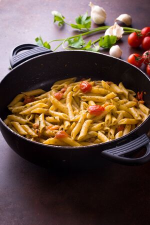 Pasta in the pan with cherry tomatoesの写真素材
