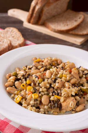Spelled, chickpea, tuna and corn salad arranged on rustic table with breadの写真素材