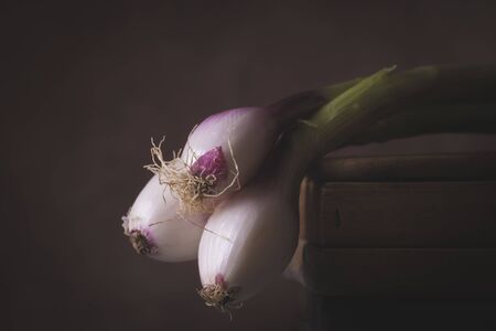 Three freshly picked red Tropea onions laid on a wooden table in a rustic settingの写真素材