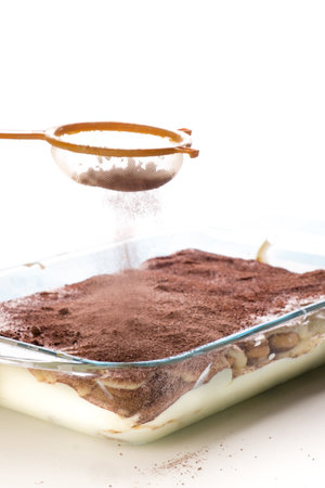 Classic tiramisu dessert in glass baking dish isolated on white backgroundの写真素材