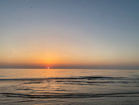 Gentle waves rolling in as the sun rises over the Adriatic Sea, creating a serene and colorful scene on the coast of Italyの写真素材