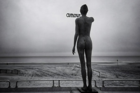 Monochrome statue overlooking North Sea shoreline, silhouetted against cloudy sky with amour lettering near Oostende, Belgiumの写真素材