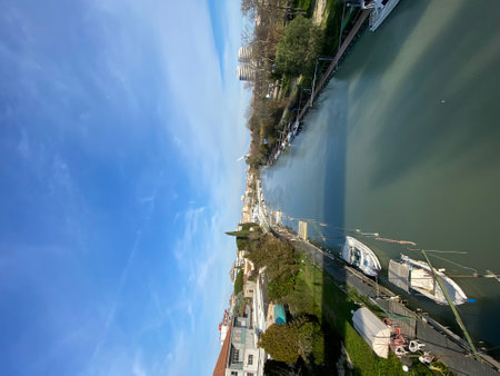 Calm river flowing through Pescara cityscape with boats moored on the banks under a vibrant blue sky, offering a serene urban landscape in Abruzzo, Italyの写真素材