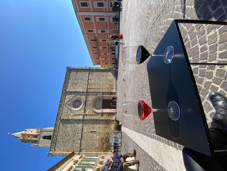Wine glasses sitting on table near Atri Cathedral's facade, historic Piazza Duomo capturing Italian architectural elegance in Abruzzo regionの写真素材
