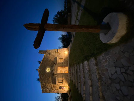 Stone chapel standing illuminated at dusk in San Valentino, Abruzzo, wooden cross highlighting architectural simplicity of historic Italian religious buildingの写真素材