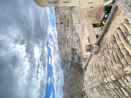 Traditional stone houses and rooftops in the Sassi di Matera, a historic district in Matera, Basilicata, Italy, under a cloudy skyの写真素材