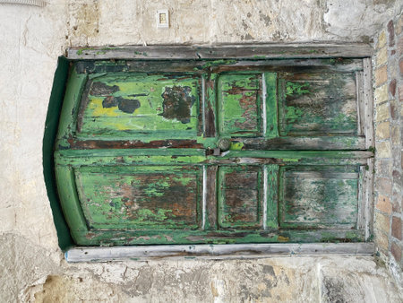 Weathered green painted wooden door in Matera, Italy, showing signs of age and deterioration, adding character to the historic architectureの写真素材