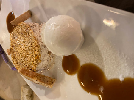 Semifreddo dessert sprinkled with almond crumbles, accompanied by vanilla ice cream and caramel drizzle on elegant restaurant plate in Pescaraの写真素材