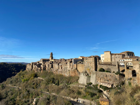 Scenic view of Pitigliano, a picturesque medieval village perched on a tufa cliff, featuring ancient buildings and a clear blue sky, in Tuscany, Italyの写真素材