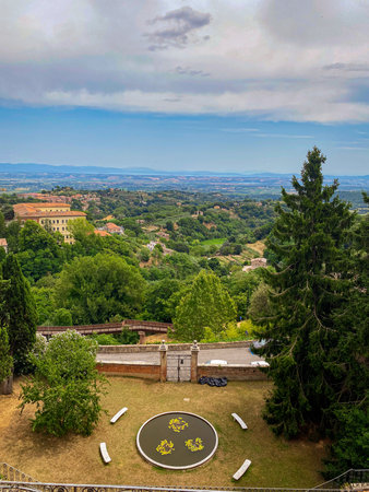 Panoramic view of the Tuscan countryside from Montepulciano, Italy, showcasing verdant vegetation and a glimpse of the town's architectureの写真素材
