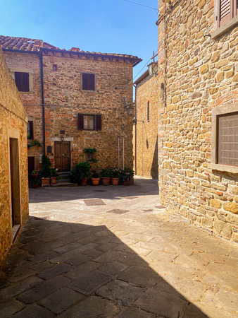 Stone houses and paved street basking in sunlight in the charming medieval village of Civitella in Val di Chiana, Tuscany, Italyの写真素材