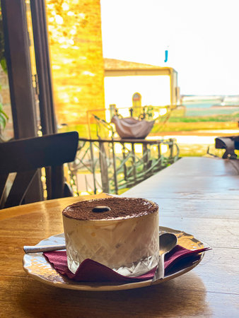 Creamy tiramisu topped with cocoa powder and coffee bean, served on a wooden table in a restaurant in Montepulciano, Tuscanyの写真素材