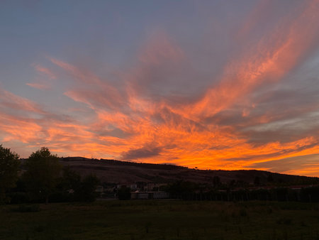 Vibrant orange-pink sky glowing above rural landscape, casting warm light over rolling hills in Pineto, Abruzzo, Italy during golden sunsetの写真素材