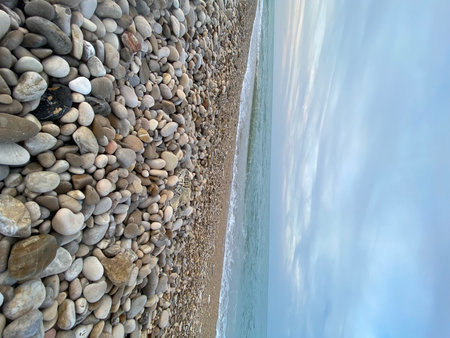 Weathered pebbles blanketing shoreline near Pineto, Italy, Adriatic waters gently lapping rocky coastal landscape under overcast skiesの写真素材