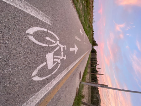 Empty bike path stretching towards the horizon, framed by a vibrant sunset sky, creating a picturesque scene in Pineto, Abruzzoの写真素材