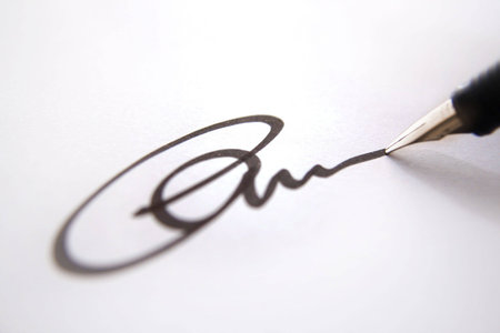 Business signature of approval, black ink on white paper close up, depth of field 