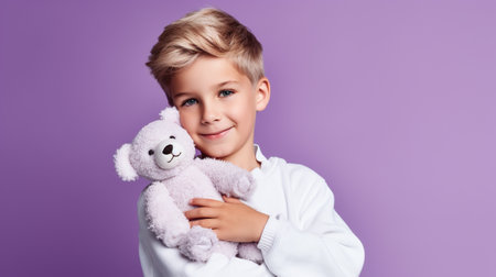 Portrait of a cute little boy with teddy bear on a purple backgroundの素材