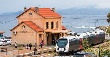 L'ILE ROUSSE, CORSICA â OCTOBER 06 2018: Tourists and locals at Ile Rousse train station move along the platform as a modern train arrives into the station.のeditorial素材