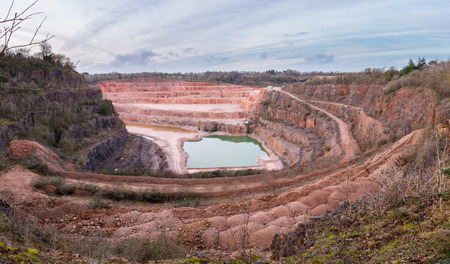 Wide angle view of Stoneycombe Quarry in Devon, England, UK. Limestone is quarried from the site and a lake has formed at the bottom surrounded by the quarry roads and equipment to pump the water out.の写真素材