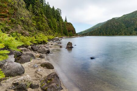 View from the waterside of Lagoa do Fogo, a crater lake on the island of SÃ£o Miguel in the Azores archipelago.  The blue lagoon is in the central caldera of the Ãgua de Pau Massif. Long exposure imageの写真素材