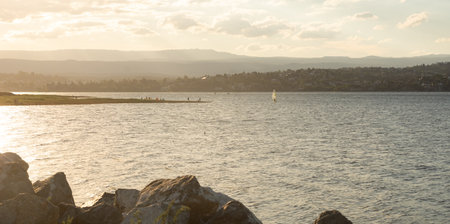 SUNSET ON A PENINSULA OF A LAKE WITH PEOPLE ON THE SHOREの写真素材