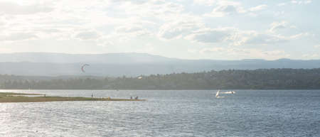 SUNSET ON A PENINSULA OF A LAKE WITH PEOPLE ON THE SHOREの写真素材
