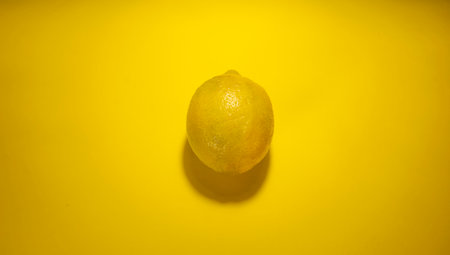 a single lemon on a yellow backgroundの写真素材