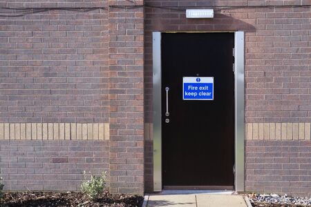Fire exit keep clear sign on hotel door for emergency guests workers peopleの写真素材
