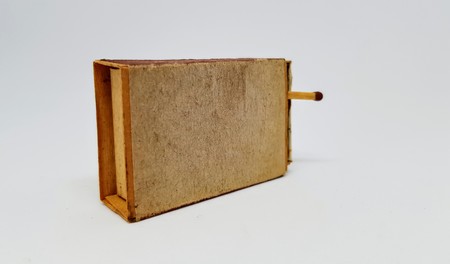 An old worn matchbox with a safety match sticking out.の写真素材