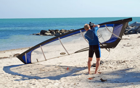 Windsurf rigging his sailboard before launching off Virginia Key in southeast florida