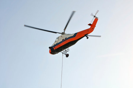 Helicopter hauling heavy equipment to the roof top of a tall building in a residential area where...