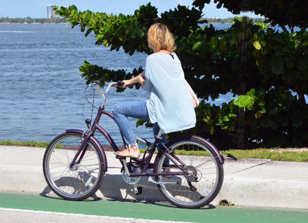 Woman on a bicycle waiting for a causeway drawbridge to open for motor and bicycle traffic.