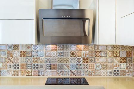 Modern home interior. Modern design of the kitchen in a bright interior. Front view. View of cooker hood, stove, wall tiles. European furniture, design, technologies.の写真素材