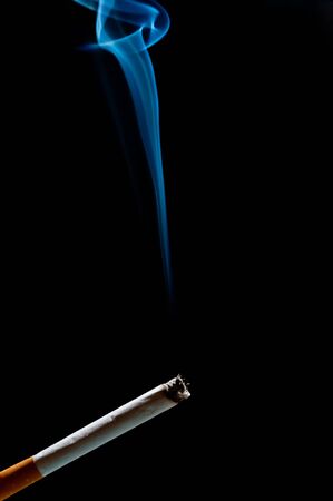 cigarette in front of black background. smoke goes upの写真素材