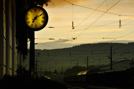 At a railway station. It is early in the morning. A clock is to be seen.